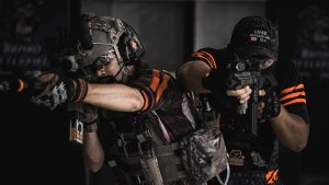 Two armed men in tactical gear engaging in realistic indoor combat training.