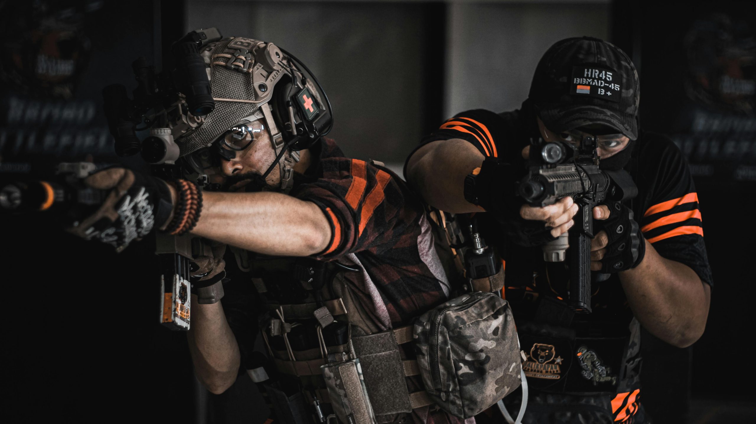 Two armed men in tactical gear engaging in realistic indoor combat training.